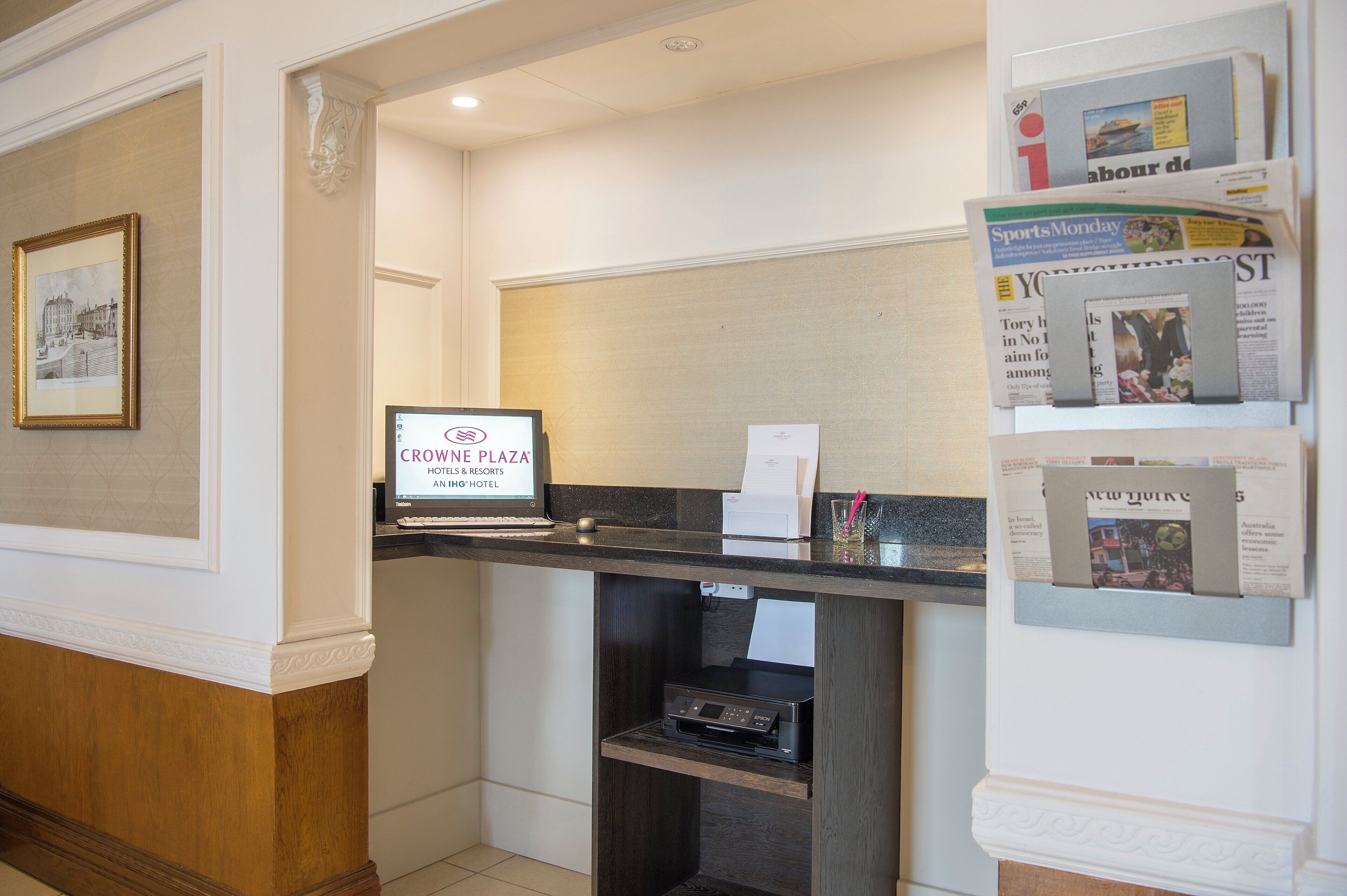 A reception desk with a digital screen displaying 'CROWNE PLAZA HOTEL & RESORTS' and a framed picture on the wall.