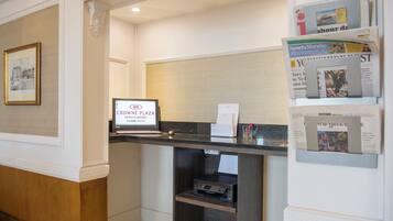 A reception desk with a digital screen displaying 'CROWNE PLAZA HOTEL & RESORTS' and a framed picture on the wall.