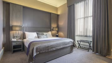 Een moderne hotelkamer met een groot bed, nachtkastjes, een venster met gordijnen en een radiator.