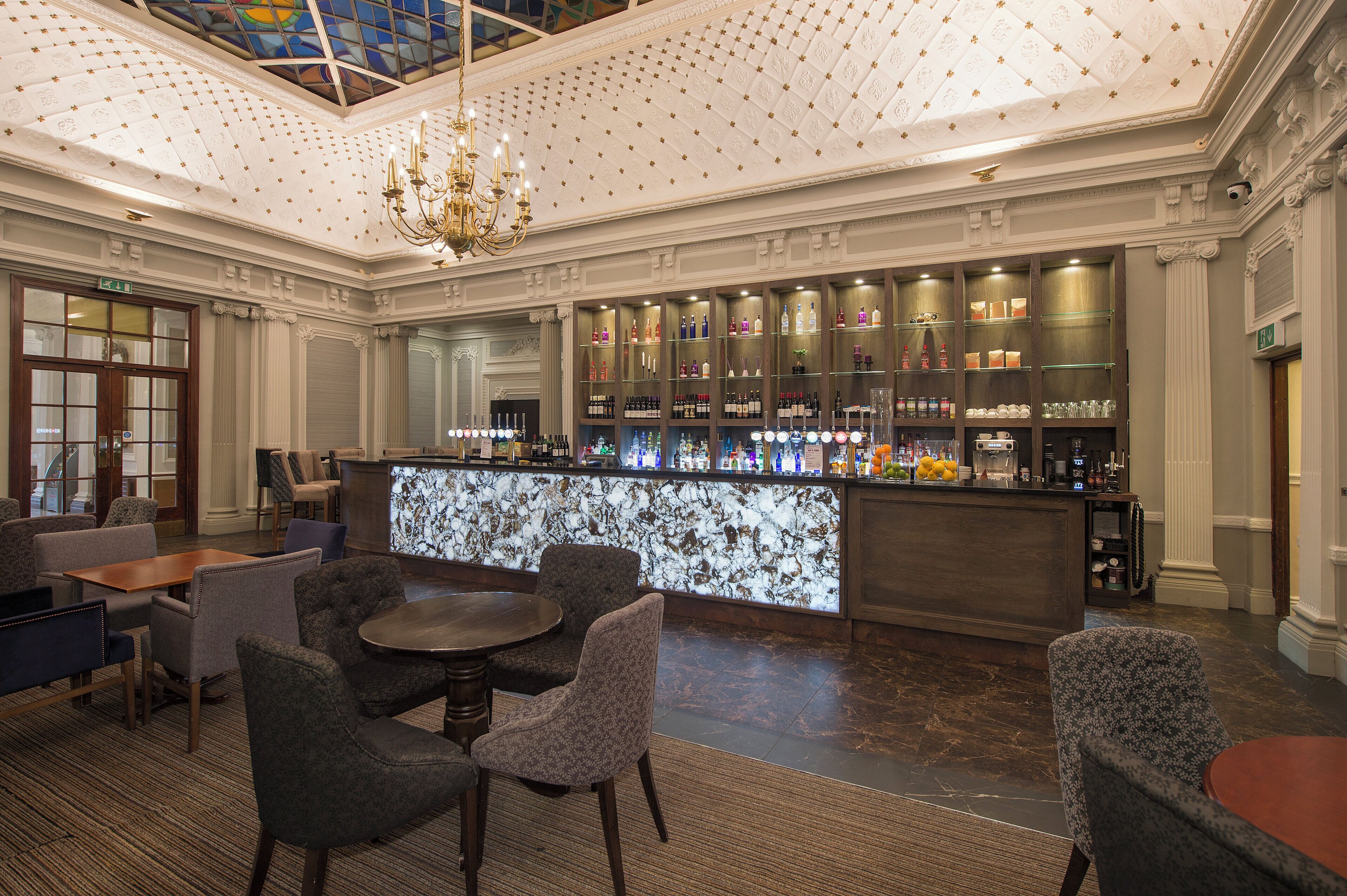A bar area with seating and a chandelier.