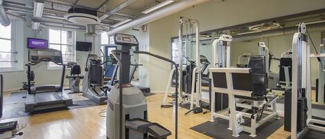 A gym with treadmills, weight machines, and a mirror wall.