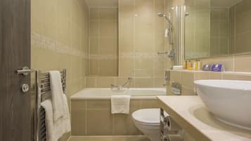 A modern bathroom with a bathtub, toilet, and large sink.