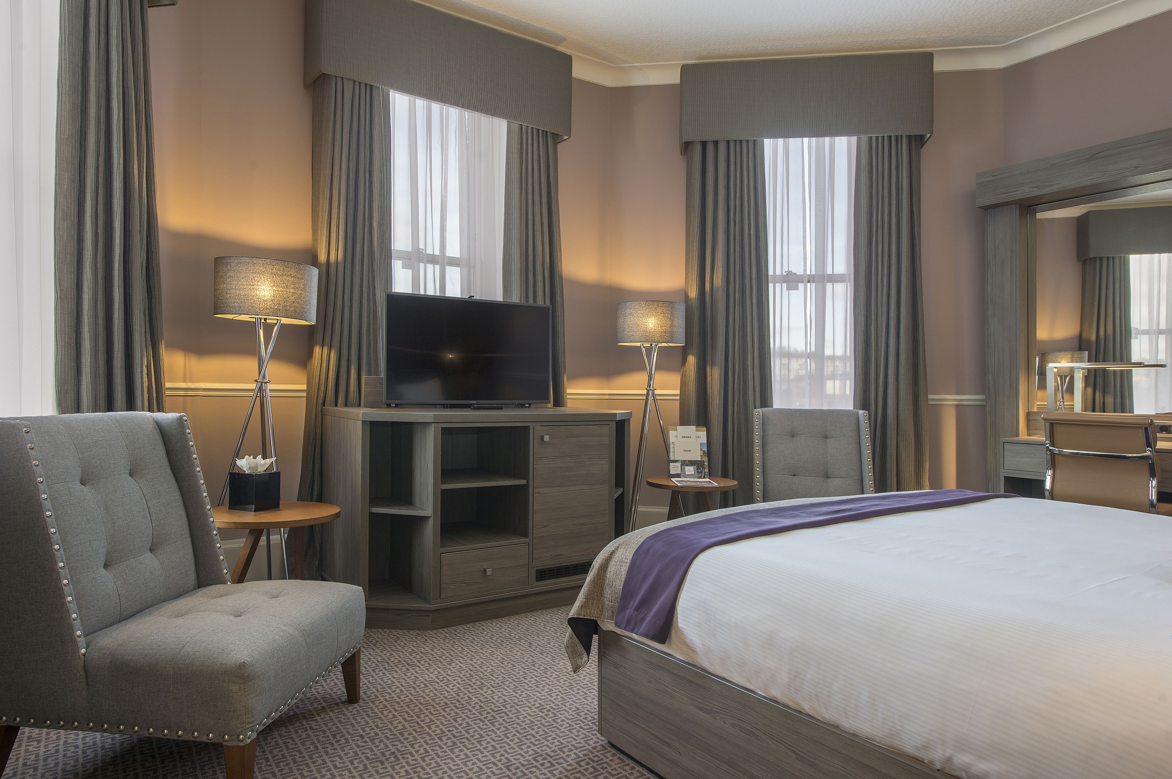 Habitación de hotel con una cama grande, televisión, escritorio y una silla.