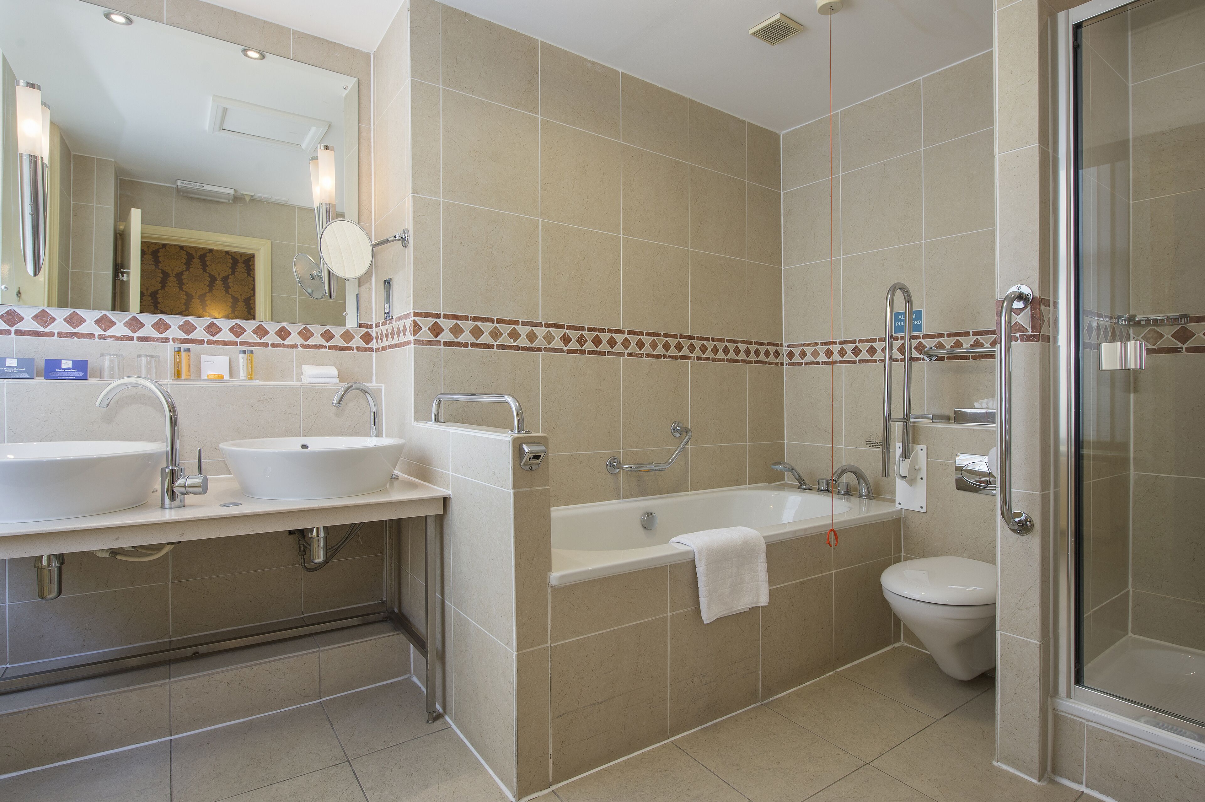 A modern bathroom with two sinks, a bathtub, and a toilet.