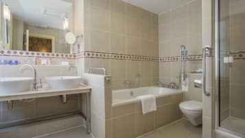 A modern bathroom with two sinks, a bathtub, and a toilet.