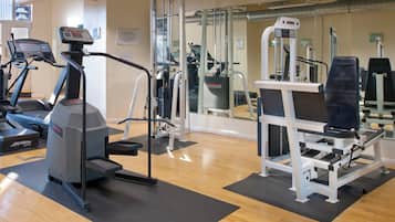 Un gimnasio con máquinas de cardio, equipo de levantamiento de pesas y espejos.