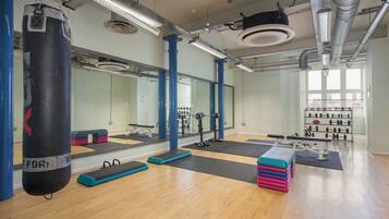 A gym with exercise equipment, mirrors, and a punching bag.