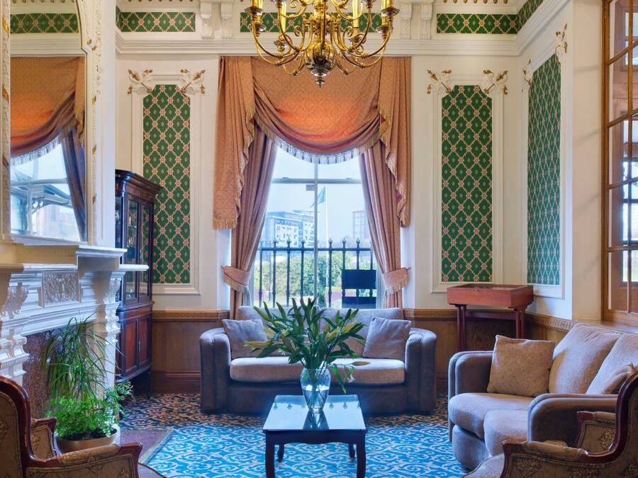 A grand room with a chandelier, patterned wallpaper, and classic furniture.