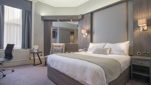 Une chambre d’hôtel avec un grand lit, un bureau et une chaise.
