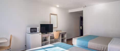 Habitación de hotel con dos camas, un escritorio con computadora y microondas, una silla y una puerta que da a otra habitación.