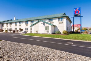 A motel with a green roof, a large sign indicating room number 6, and a Coastal Farm & Ranch sign.