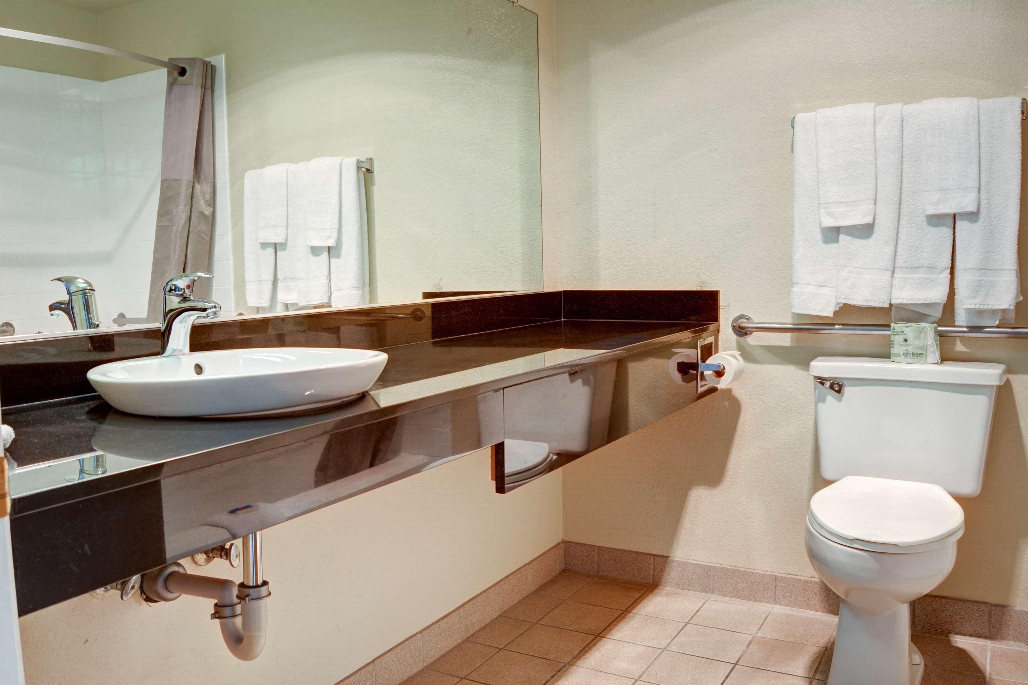 A modern bathroom with a sink, mirror, and toilet.
