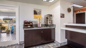A hotel reception area with a coffee machine, a clock, and a sign indicating check-in times. - Motel 6 The Dalles, OR (The Dalles)