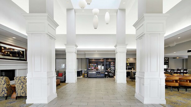 A spacious lobby with a central seating area, a fireplace, and a retail section. - Hilton Garden Inn Champaign/Urbana (Champaign)