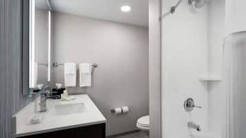 Un baño moderno con lavamanos, espejo y ducha blancos.