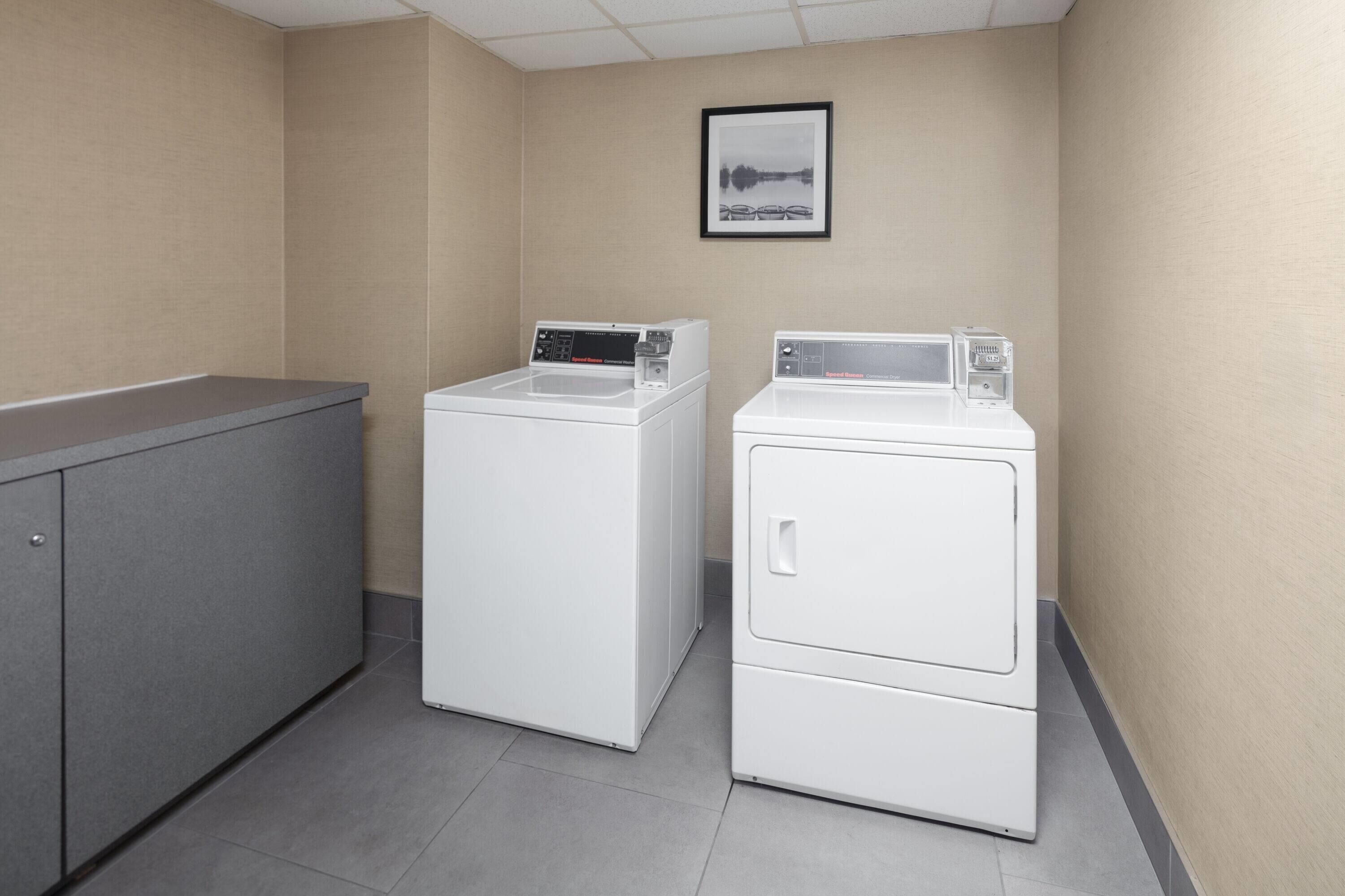 Une buanderie avec deux machines à laver blanches et un meuble gris.