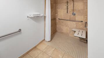 A handicap-accessible bathroom with a shower, grab bars, and a white towel rack.