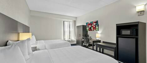Quarto de hotel com duas camas, uma escrivaninha, televisão, micro-ondas e janela com cortinas.