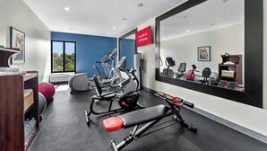 Un gimnasio con equipamiento de ejercicio, una estación de agua y un cartel que indica acceso a Wi-Fi gratuito.