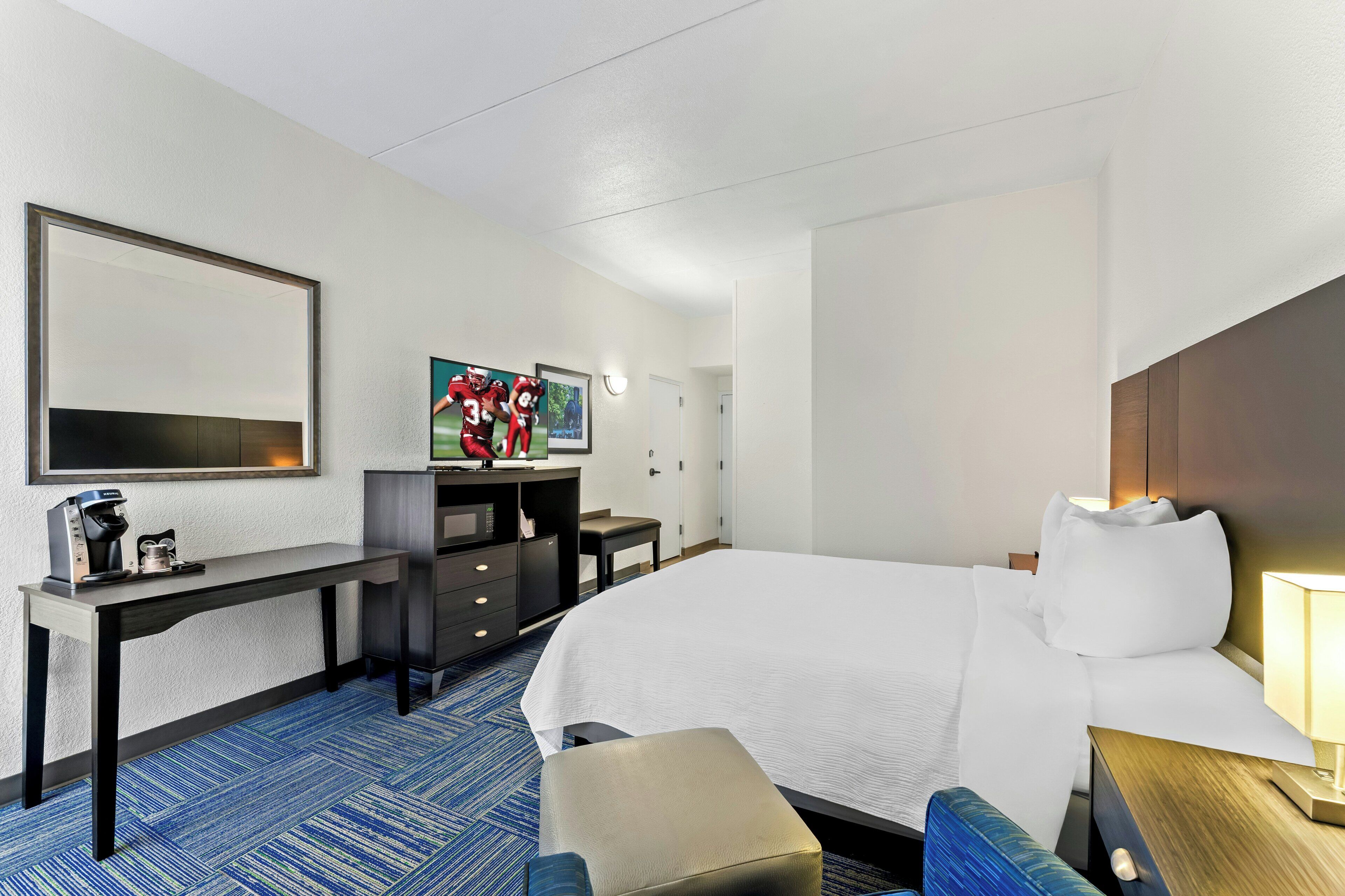Une chambre d’hôtel comprenant un lit, un bureau avec une machine à café, une télévision et un coin salon.