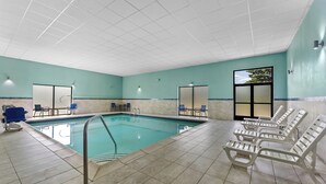 An indoor swimming pool with tiled flooring, lounge chairs, and a view of trees through a window. - Allentown Park Hotel by The Red Collection (Allentown)