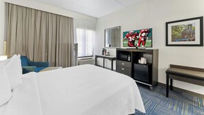 A hotel room with a large bed, a desk with a computer, a television, a mirror, and a framed picture on the wall. - Allentown Park Hotel by The Red Collection (Allentown)