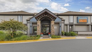 A Sonesta ES Suites building with a modern design, featuring a prominent entrance with a stone archway and a number "13700" above the door.