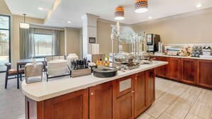 A modern kitchen with a central island, equipped with various appliances and utensils, and a seating area with a table and chairs.