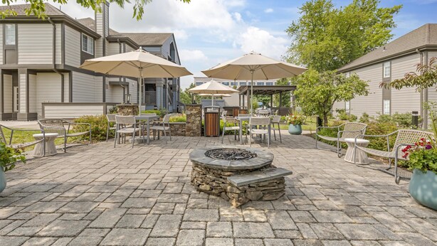 A patio area with stone flooring, outdoor furniture, and umbrellas.