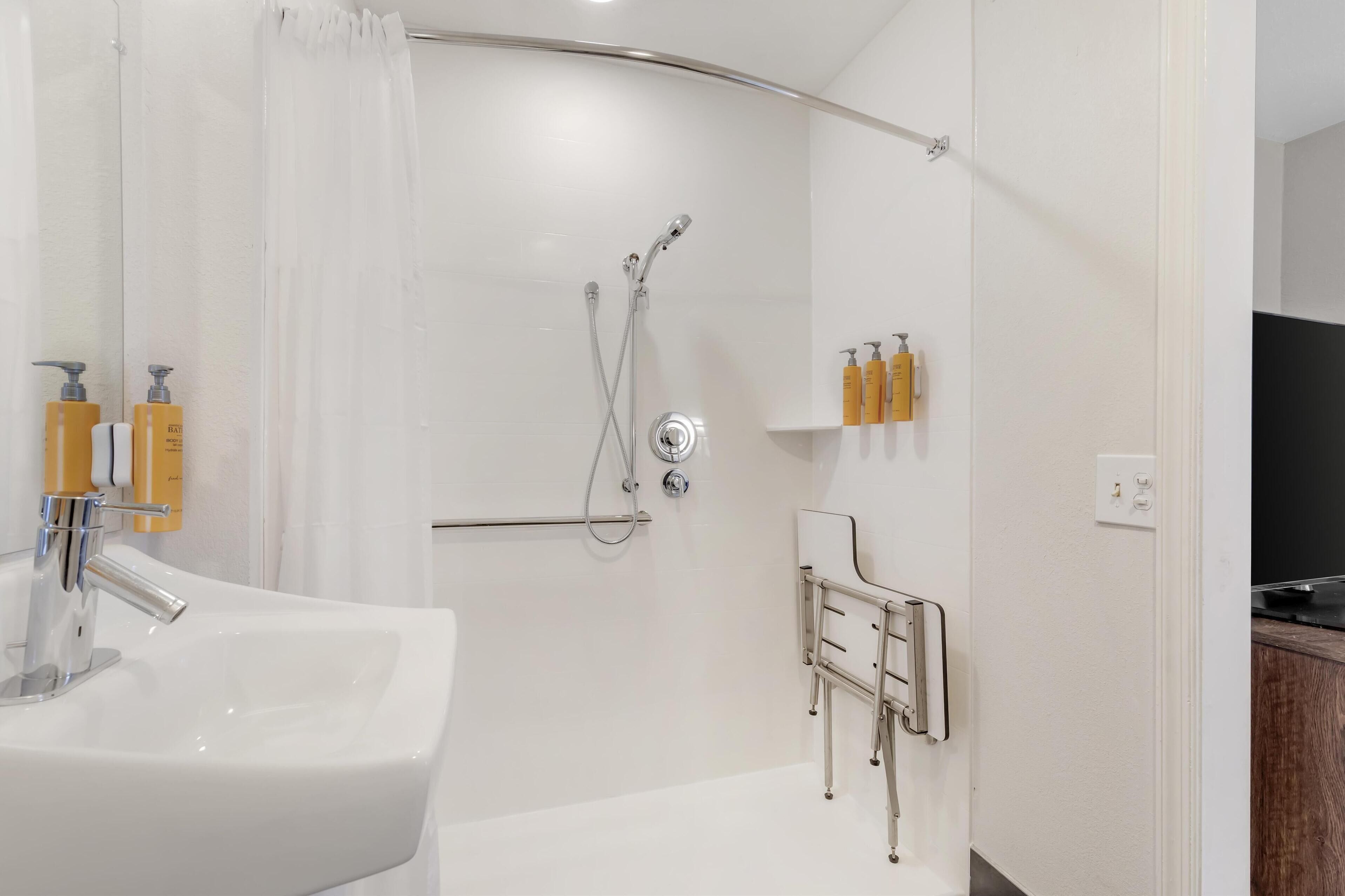 A modern bathroom with a white sink, shower, and toilet.