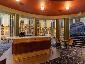 A bar area with a counter, seating, and a staircase. - Nest Hotel Paris la Défense - MGallery Collection (Puteaux)