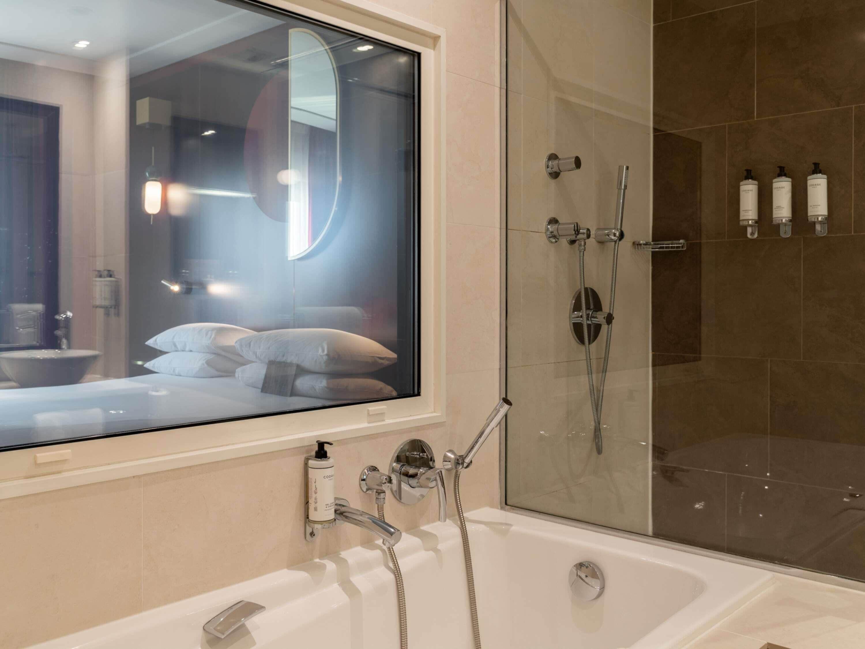 A modern bathroom with a glass-enclosed shower, a bathtub, and a large mirror.