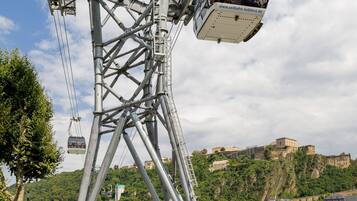 Sistema de teleférico con vistas despejadas del paisaje circundante, incluyendo un castillo en una colina y un río.