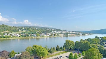 Blick auf eine Stadt an einem Flussufer mit Parkplatz und Bäumen.