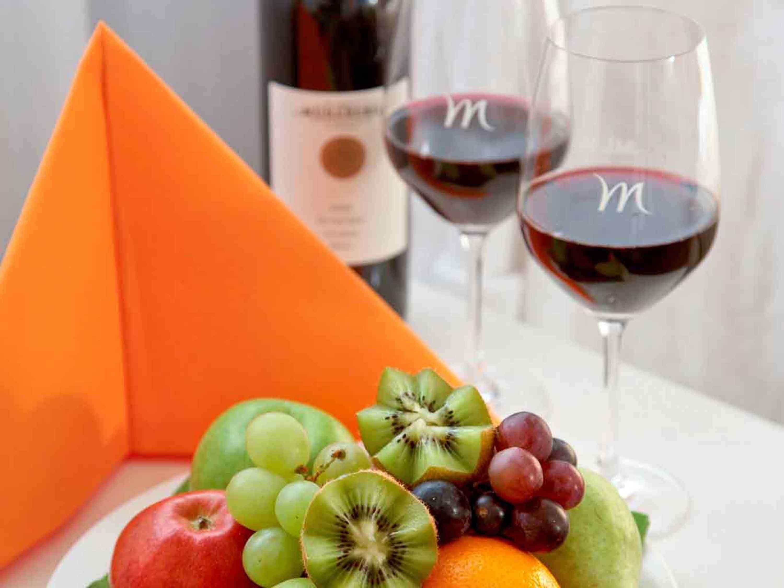 Una composición de frutas con una botella de vino y copas.