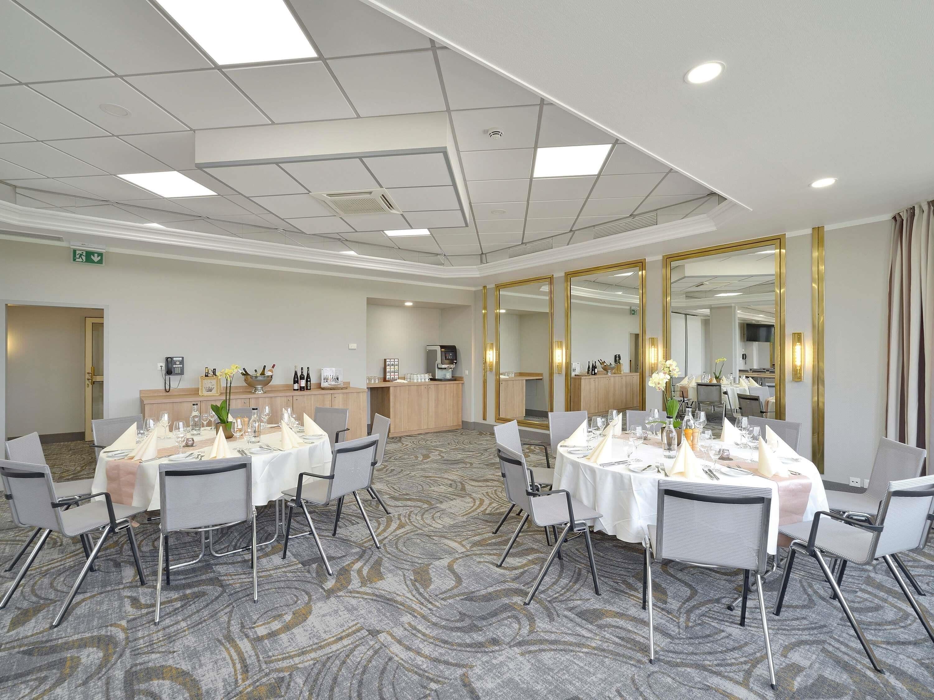 A conference room with tables set for dining, a reception desk, and a large mirror.