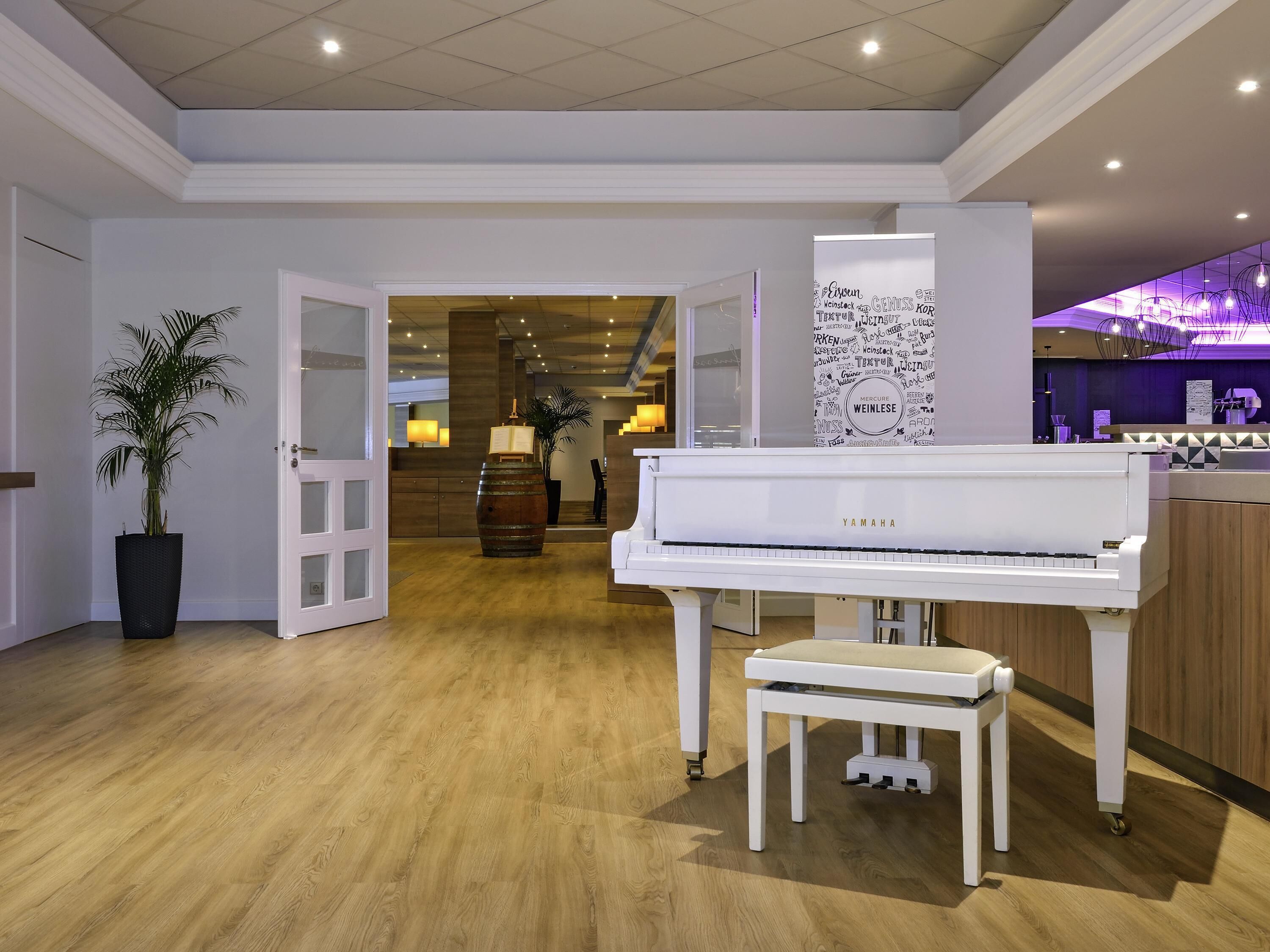 A spacious room with a grand piano, a potted plant, and a wooden cabinet.