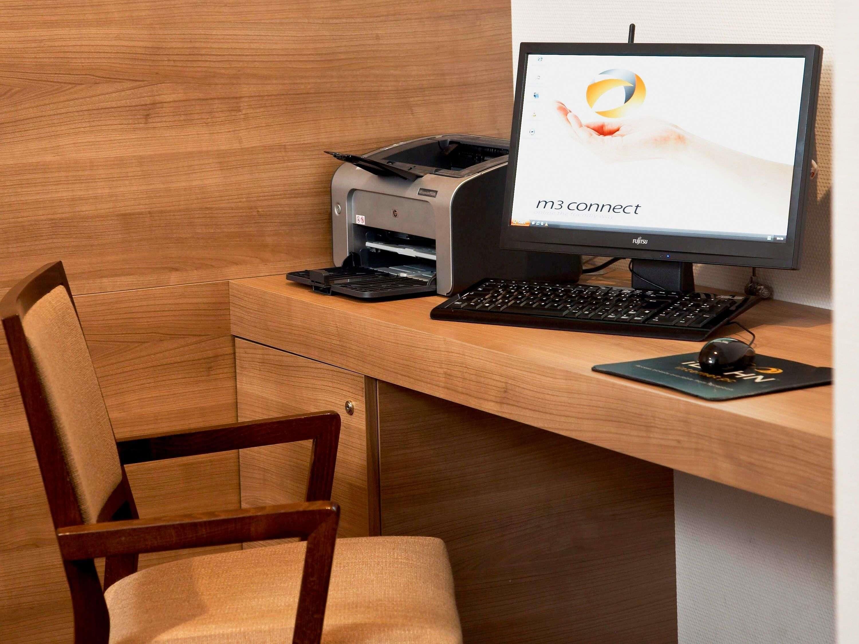 Un escritorio de madera con una computadora de escritorio, teclado, ratón y un monitor que muestra un logotipo.