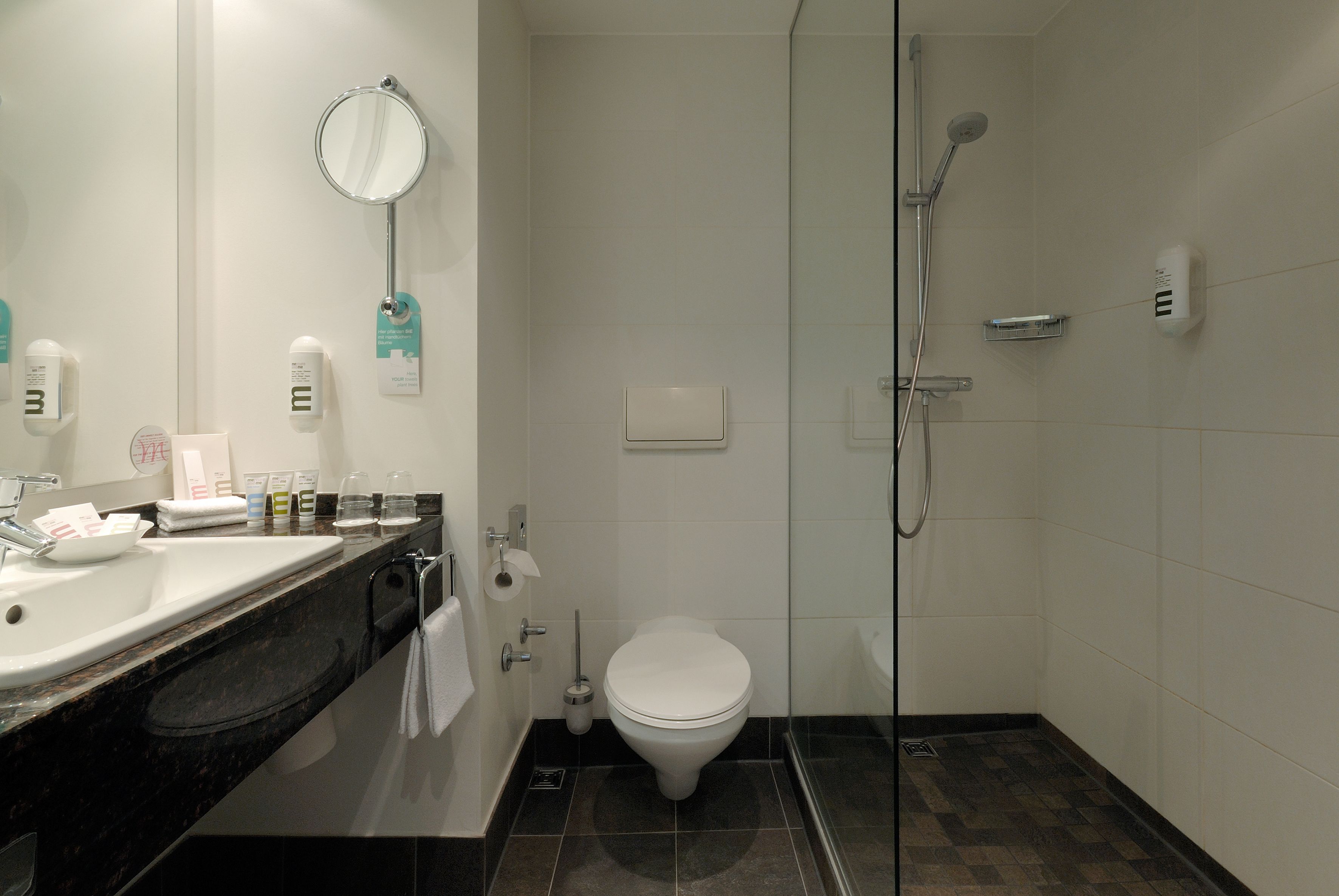 Un baño moderno con lavamanos, inodoro y ducha con mampara de vidrio.