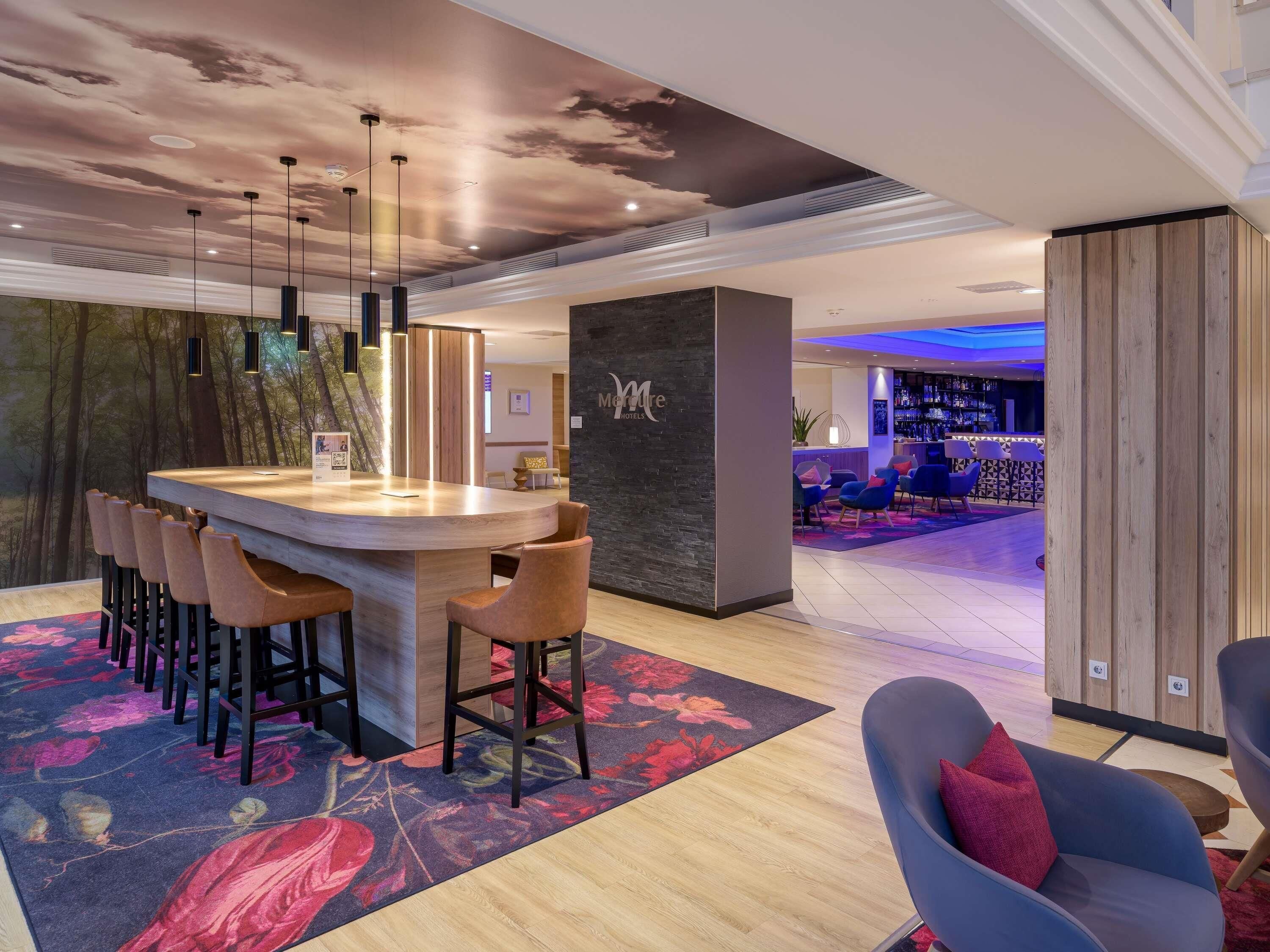 Un moderno vestíbulo de hotel con una zona de bar, arreglos de asientos y un techo decorativo.