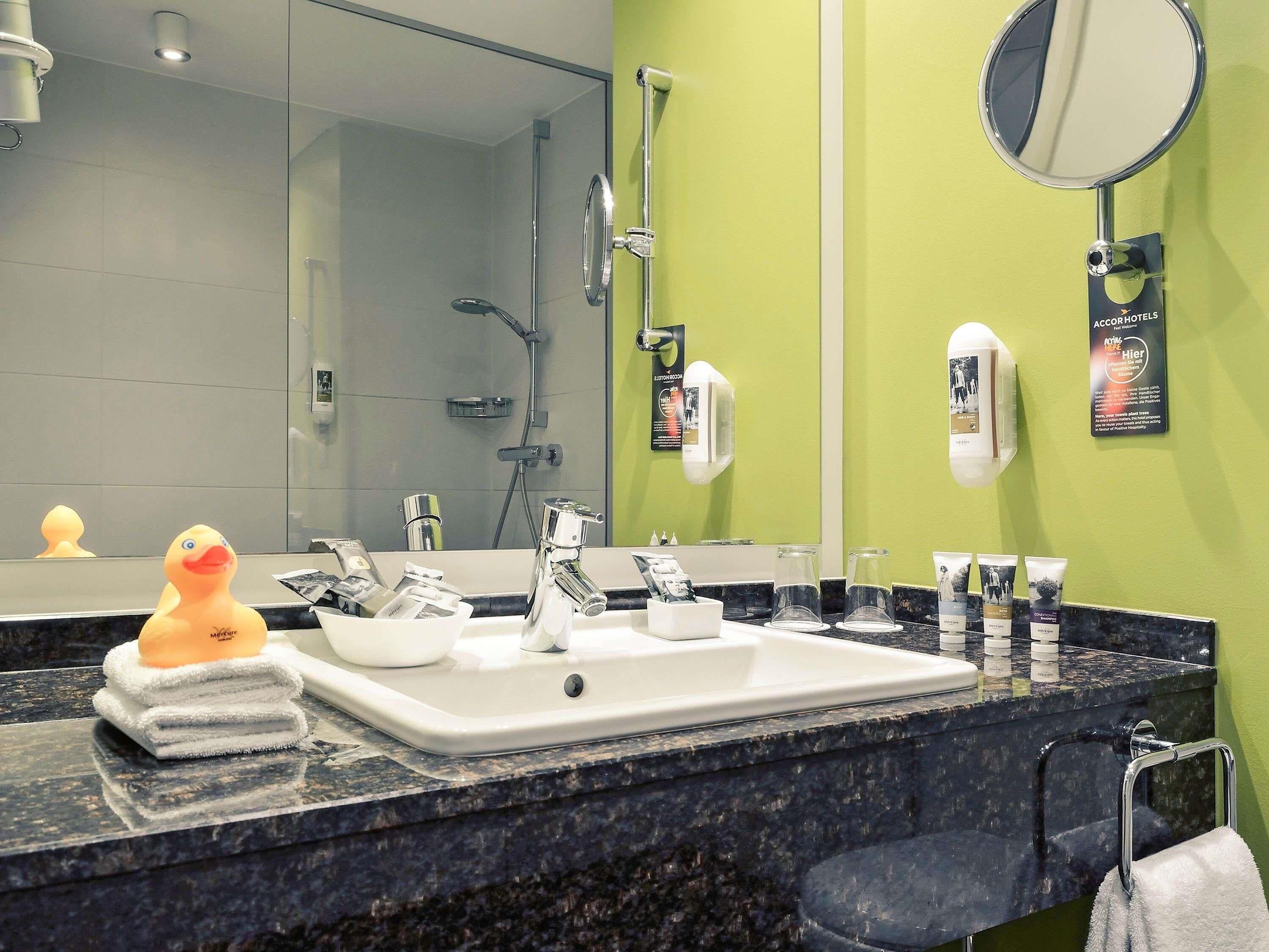 Un baño con lavamanos, espejo y artículos de aseo.