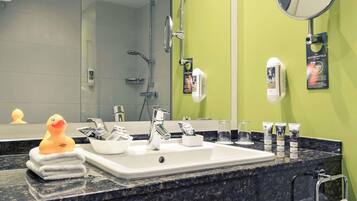 Un baño con lavamanos, espejo y artículos de aseo.