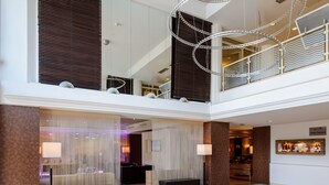 Un vestíbulo espacioso con techo alto, un área de estar central y una escalera que conduce a un nivel superior.