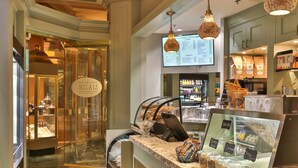 A cafe interior with a menu board, a cash register, and a display of various beverages. - The Windsor Court (New Orleans)