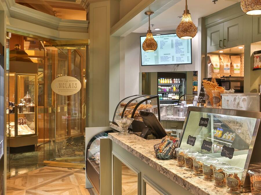 A cafe interior with a menu board, a cash register, and a display of various beverages.