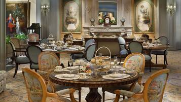 A formal dining room with ornate furniture, a chandelier, and a large mirror.
