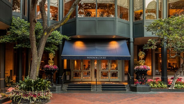 A hotel entrance with a dark awning, glass doors, and a staircase leading up. - The Windsor Court (New Orleans)