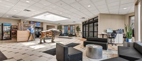 A spacious lobby with a reception desk, seating area, and a large statue.