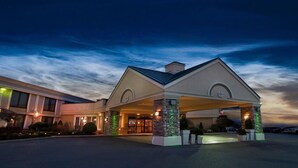 A hotel with a covered entrance, stone pillars, and a well-lit facade.