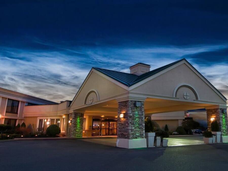 A hotel with a covered entrance, stone pillars, and a well-lit facade.